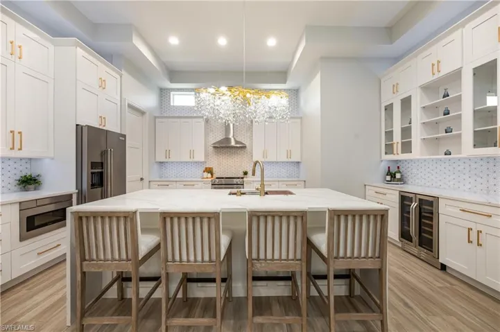 Kitchen with glass insert cabinets, white cabinetry, light stone counters, and recessed lighting