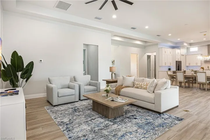 Living area with light wood-style flooring, recessed lighting, a raised ceiling, and ceiling fan