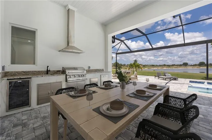 View of patio with exterior kitchen, a sunroom, a lanai, an outdoor pool, and outdoor dining area
