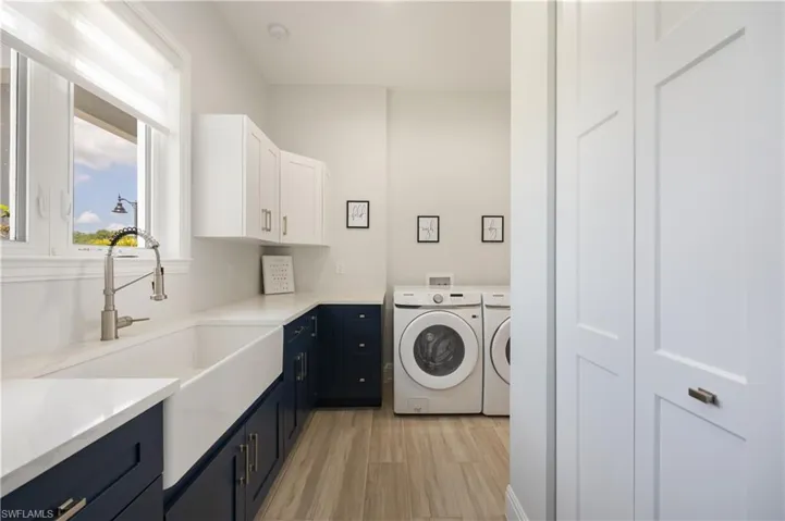 Laundry room featuring light wood finished floors, washer and clothes dryer, and cabinet space