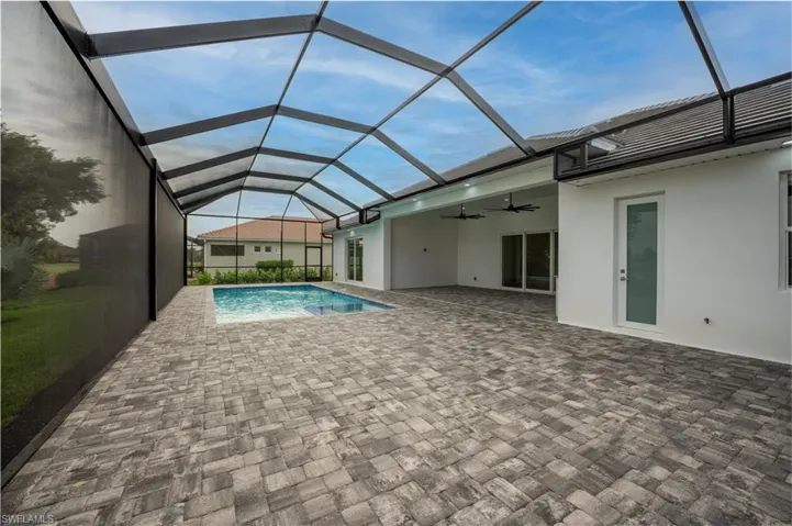 Swimming pool featuring a sunroom, a ceiling fan, a patio, and glass enclosure