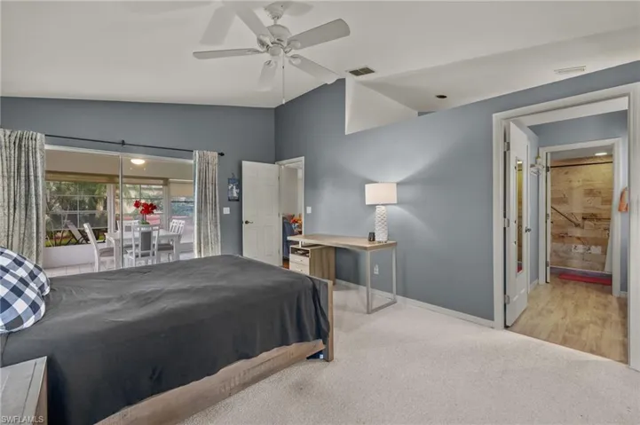 Bedroom with ceiling fan, light carpet, vaulted ceiling, and access to outside