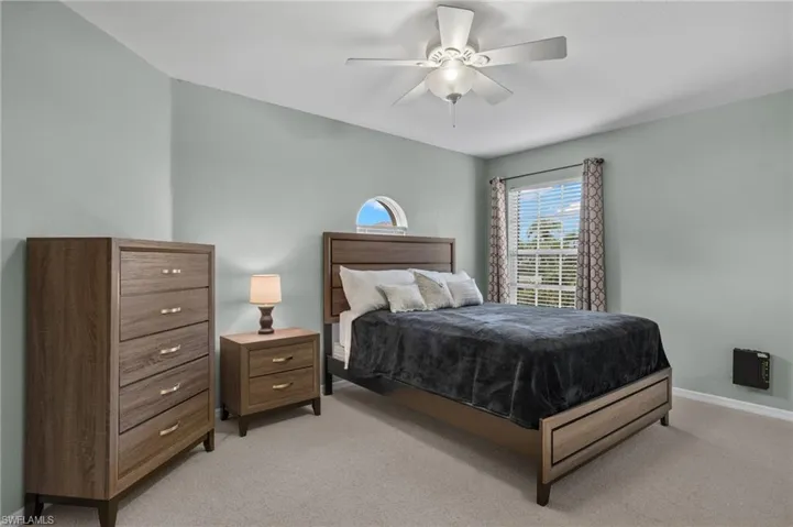 Bedroom with ceiling fan and light carpet