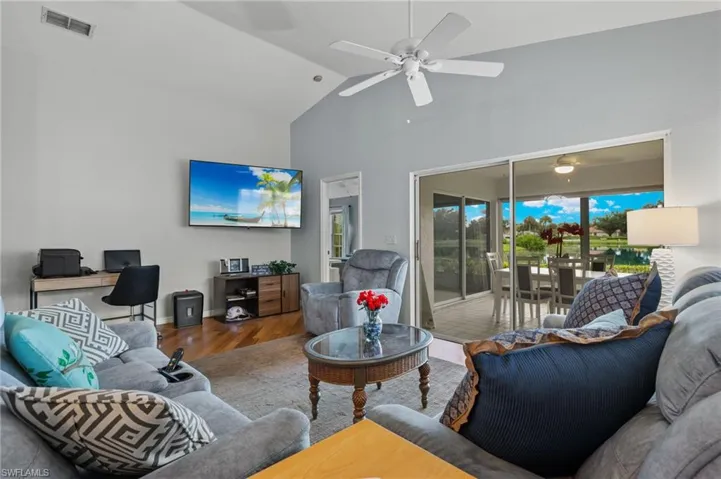 Living room featuring high vaulted ceiling, hardwood / wood-style flooring, and ceiling fan
