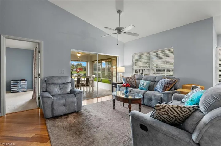 Carpeted living room featuring ceiling fan and high vaulted ceiling