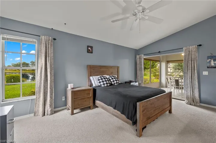Bedroom with multiple windows, ceiling fan, light colored carpet, and access to exterior