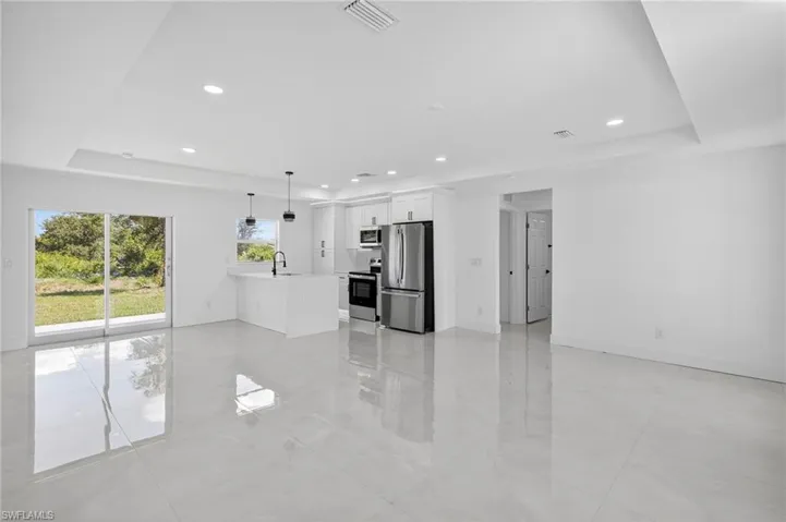 Unfurnished living room featuring a raised ceiling, recessed lighting, and light tile patterned floors