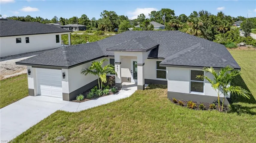 View of front of house featuring stucco siding, a front yard, roof with shingles, and an attached garage