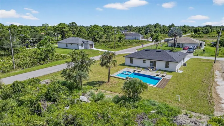 View of subject property with a pool and a tree filled landscape