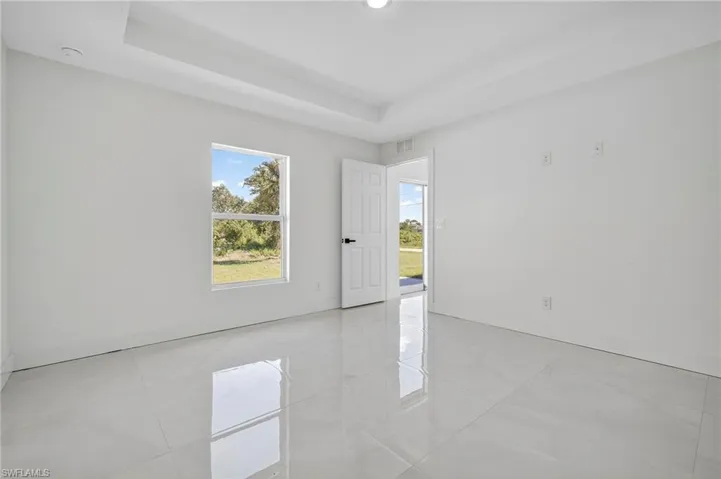 Spare room featuring healthy amount of natural light, light tile patterned floors, and a raised ceiling