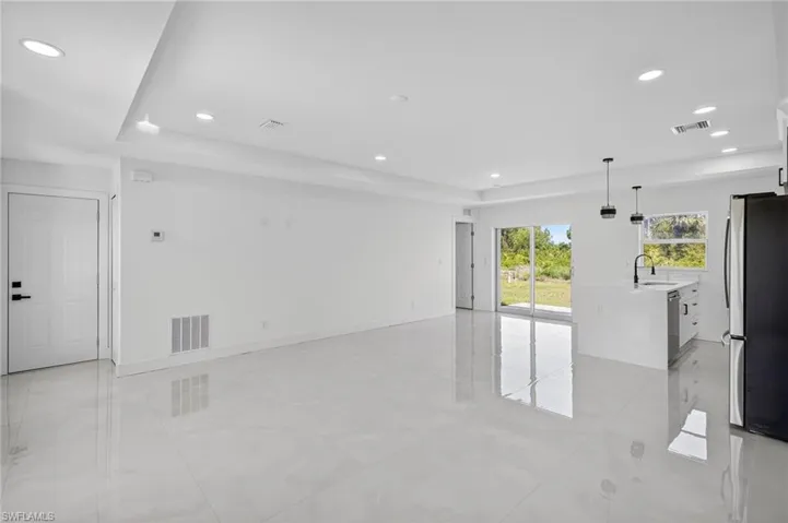 Unfurnished living room with recessed lighting, light tile patterned floors, and a tray ceiling