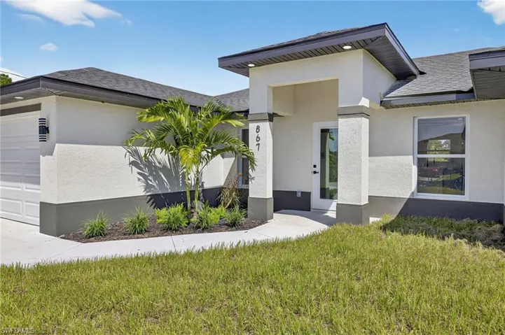 View of front of property with stucco siding, a front lawn, an attached garage, and a shingled roof