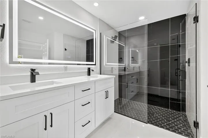 Bathroom featuring light tile patterned flooring, double vanity, a stall shower, and recessed lighting