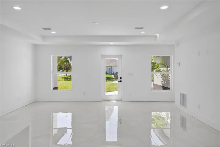 Empty room featuring healthy amount of natural light, recessed lighting, a tray ceiling, and light tile patterned flooring
