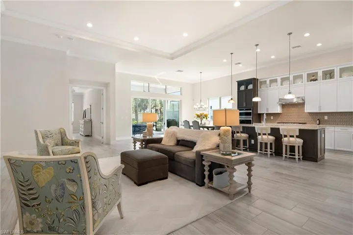 Living room with a chandelier, recessed lighting, light wood-style flooring, and crown molding