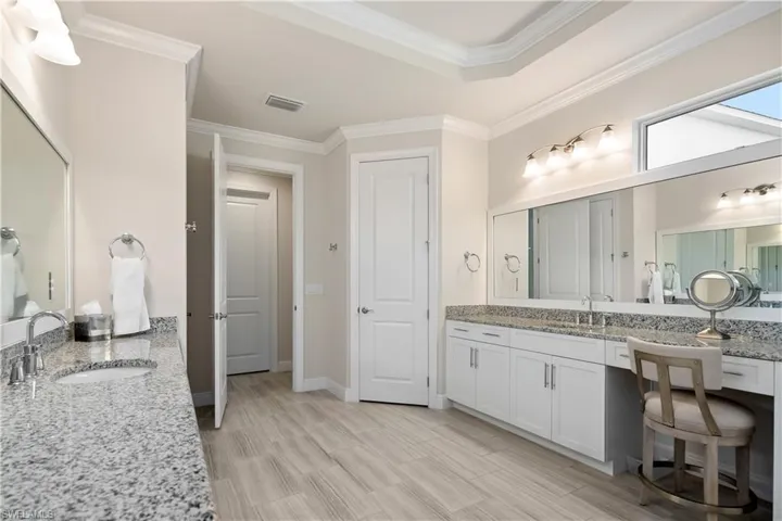 Full bath with two vanities, crown molding, and wood tiled floors