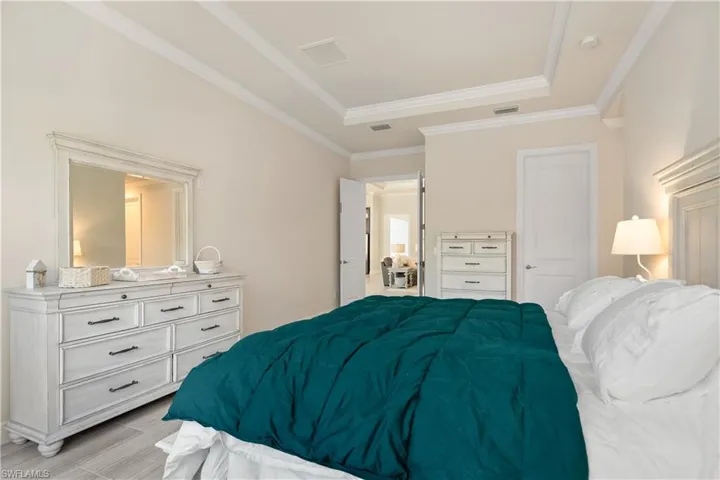 Bedroom featuring ornamental molding, wood finish floors, and a raised ceiling