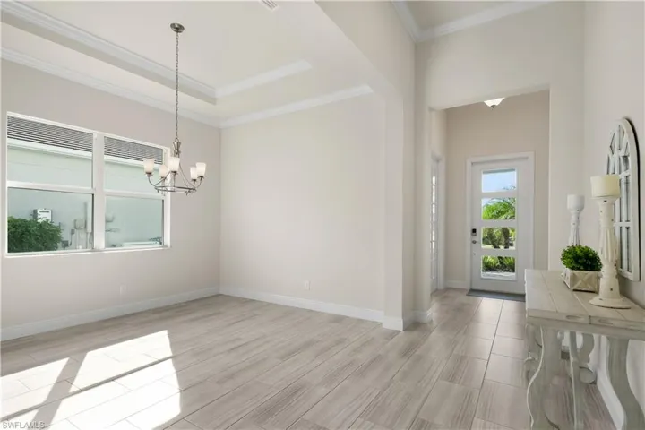 Foyer entrance with a chandelier, wood finish floors, and crown molding