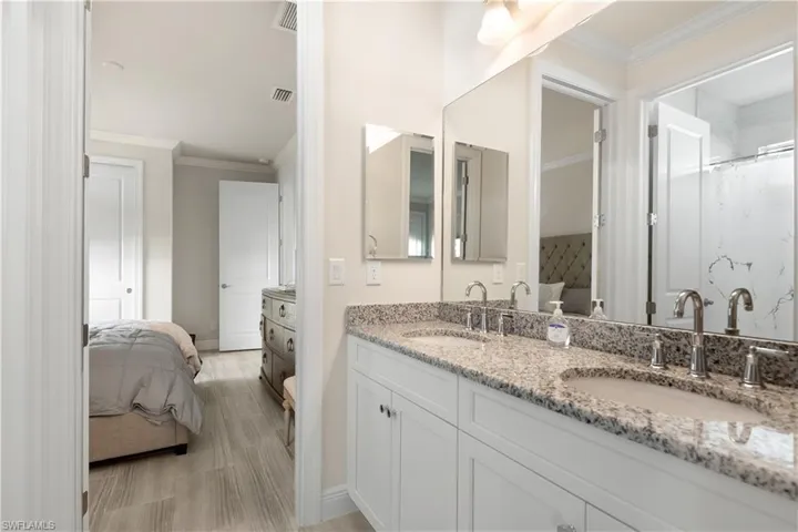 Ensuite bathroom featuring crown molding, double vanity, and a shower with curtain