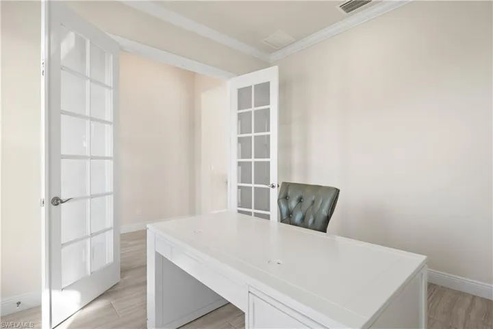 Unfurnished office featuring light wood-style floors, ornamental molding, and french doors