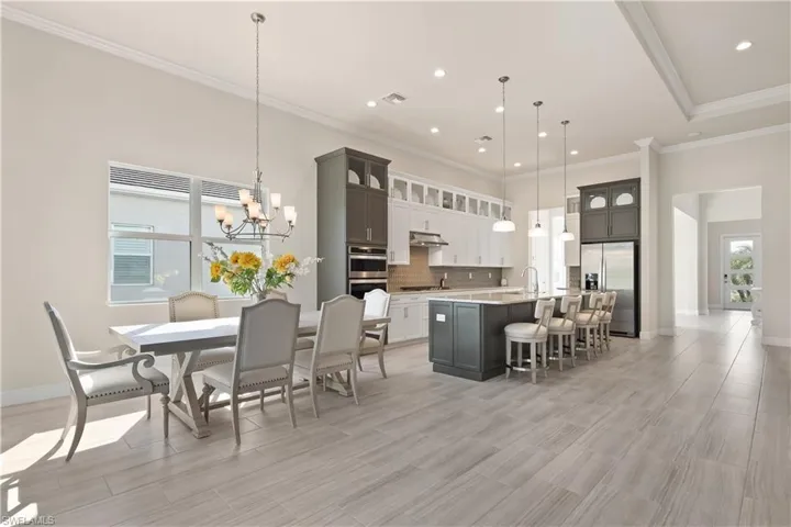 Kitchen with glass insert cabinets, a chandelier, stainless steel appliances, a kitchen breakfast bar, and a kitchen island with sink