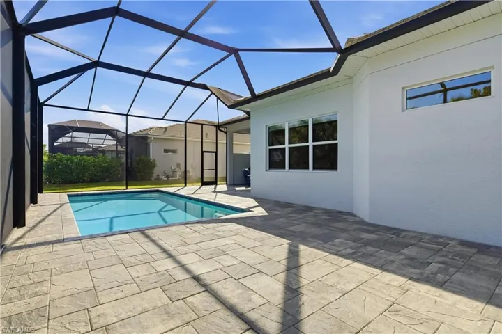 Outdoor pool featuring a sunroom, a patio, and glass enclosure