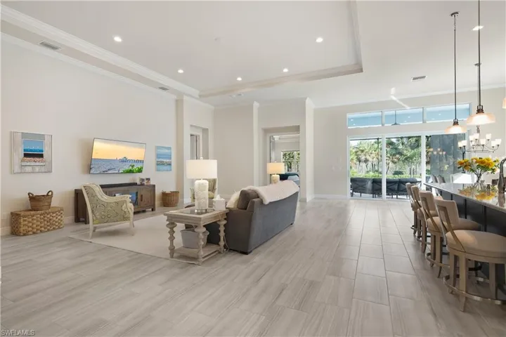 Living area featuring recessed lighting, a towering ceiling, a chandelier, ornamental molding, and a raised ceiling