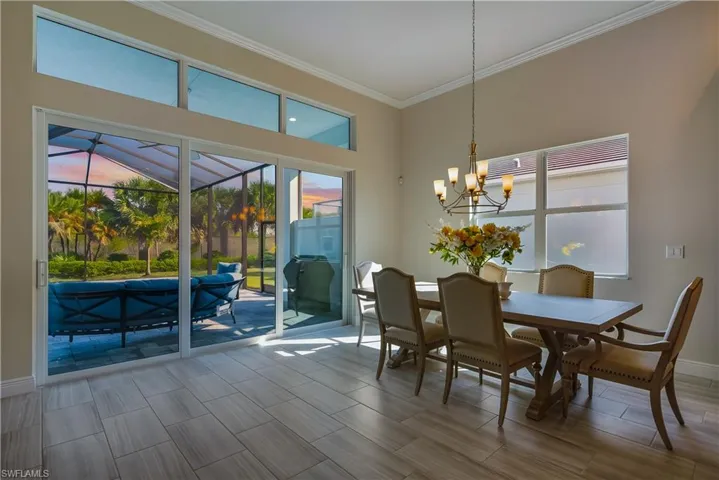 Dining room featuring ornamental molding, wood tiled floors, a chandelier, and a sunroom