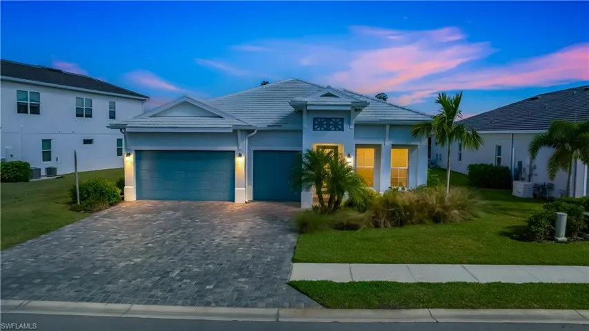 View of front of home with a yard, decorative driveway, stucco siding, an attached garage, and a tile roof