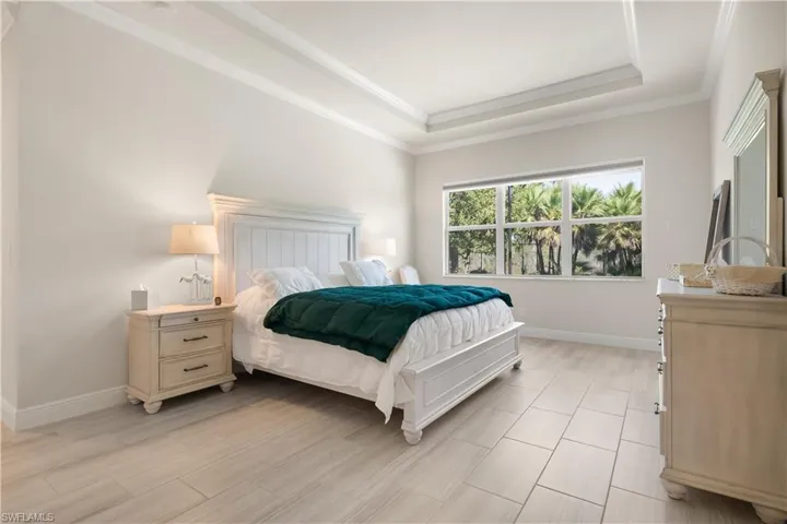 Bedroom featuring a raised ceiling, wood finish floors, and ornamental molding