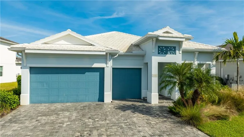 View of front of property with decorative driveway, a garage, stucco siding, and a tiled roof