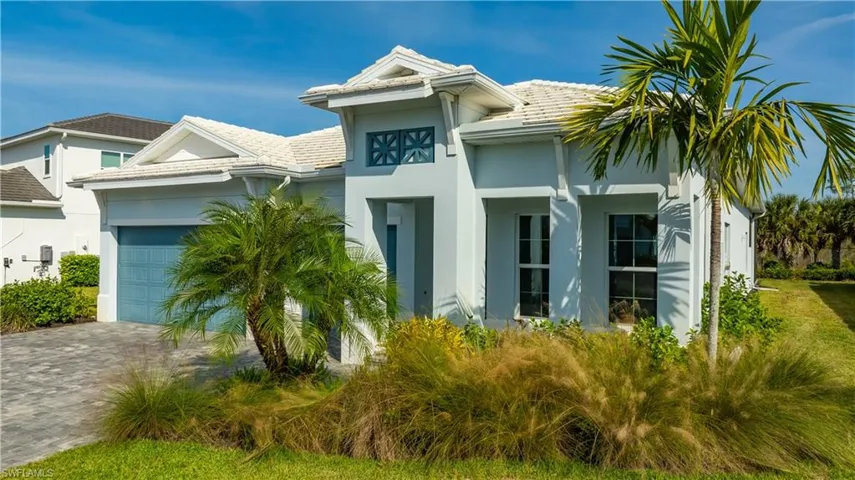 View of front facade featuring an attached garage, stucco siding, and decorative driveway