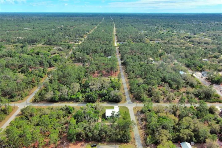 Aerial view of property and surrounding area featuring a forest