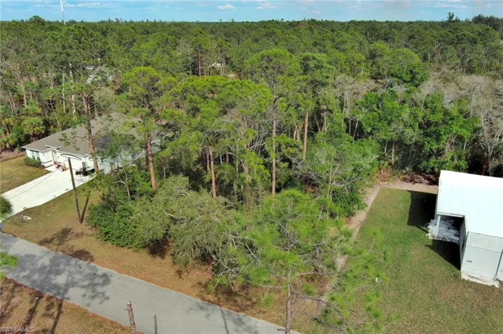 Aerial view of property and surrounding area with a heavily wooded area