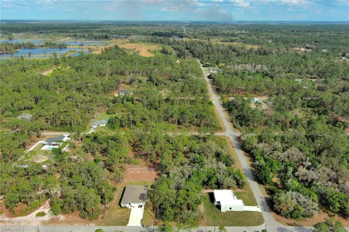 View of property location with a heavily wooded area and a nearby body of water