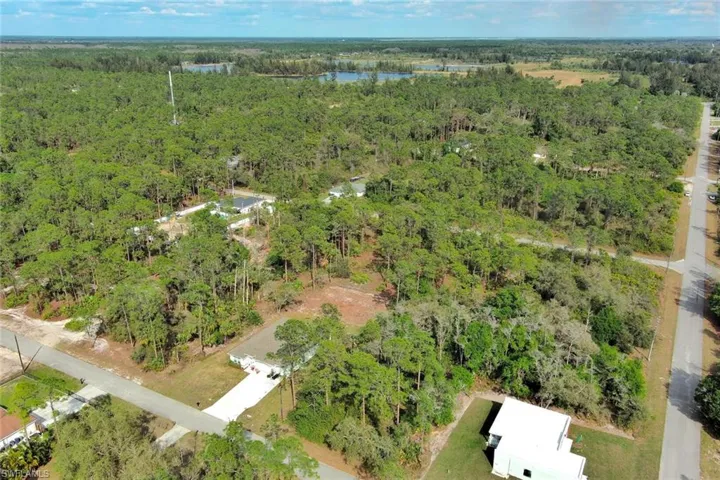 Aerial view of property and surrounding area with a forest and a large body of water