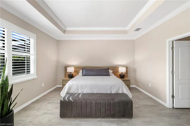Primary with tray ceiling, crown molding, and plantation shutters