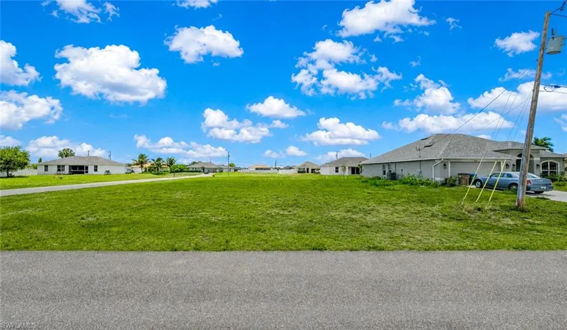 Expansive cleared lot featuring green grass and a paved road frontage