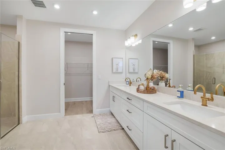 Full bathroom featuring a spacious closet, a shower stall, double vanity, and recessed lighting