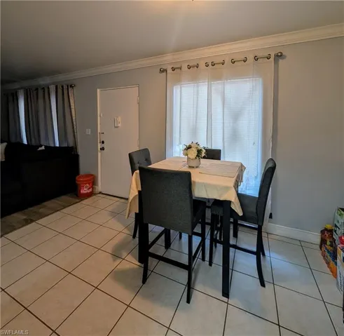 Dining area with light tile patterned floors and ornamental molding