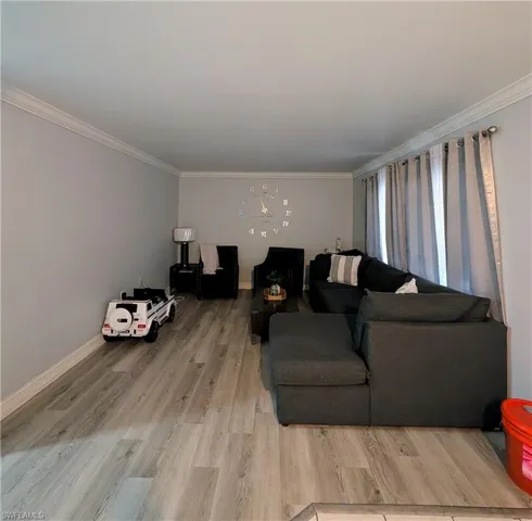 Living room with ornamental molding and light wood-type flooring