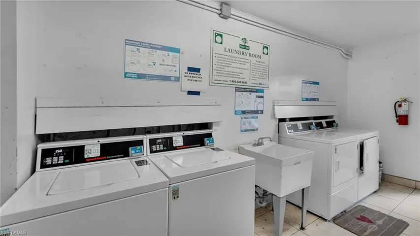 Laundry room with sink, light tile patterned floors, and independent washer and dryer