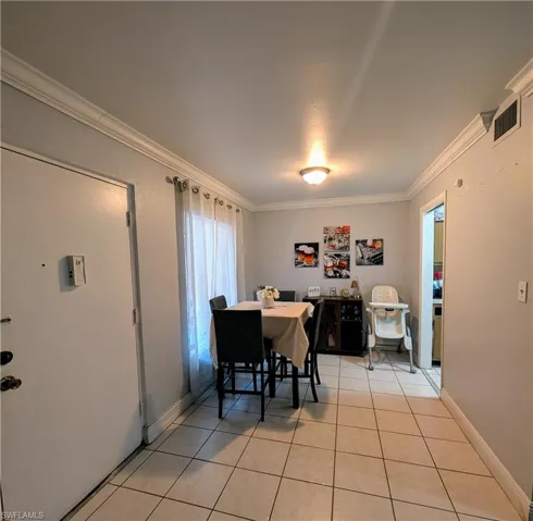 Dining area with ornamental molding and light tile patterned floors