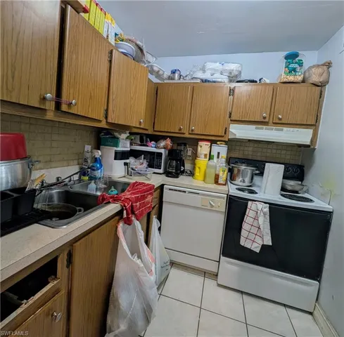 Kitchen featuring sink, light tile floors, electric range, white dishwasher, and backsplash