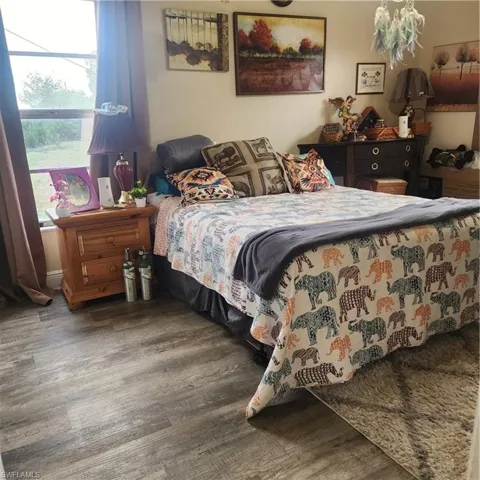 Light-filled room featuring wood-finish flooring, a window with drapery, and neutral wall paint