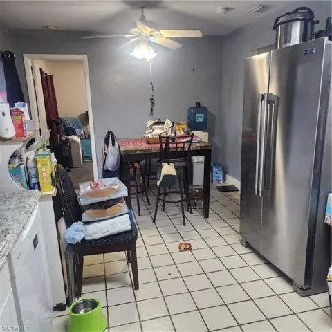 Kitchen space featuring tile flooring, a built-in ceiling fan with light fixture, light-toned walls, and a pass-through opening to an additional room