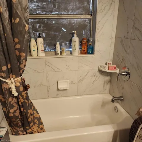 White porcelain bathtub with chrome fixtures and white marbled wall tiling