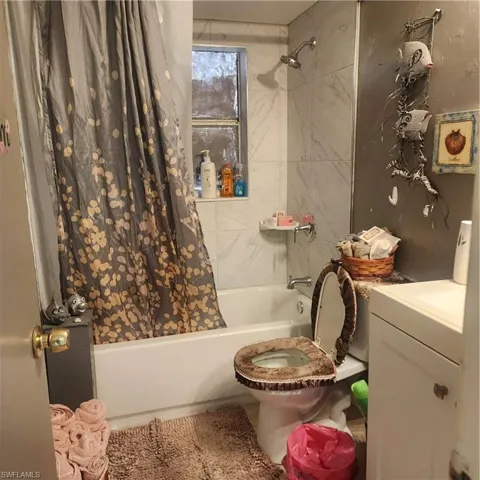 Bathroom featuring a shower-tub combination with white subway tile surround, chrome showerhead, and a window