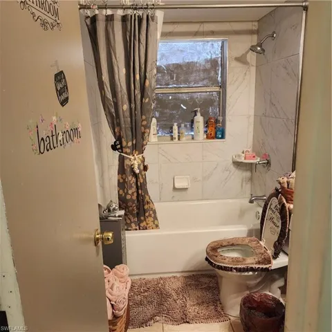 Bathtub with surrounding tile walls and a window