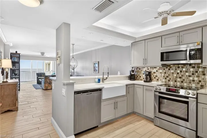 Kitchen with gray cabinetry, stainless steel appliances, ceiling fan, crown molding, and wood tiled floors